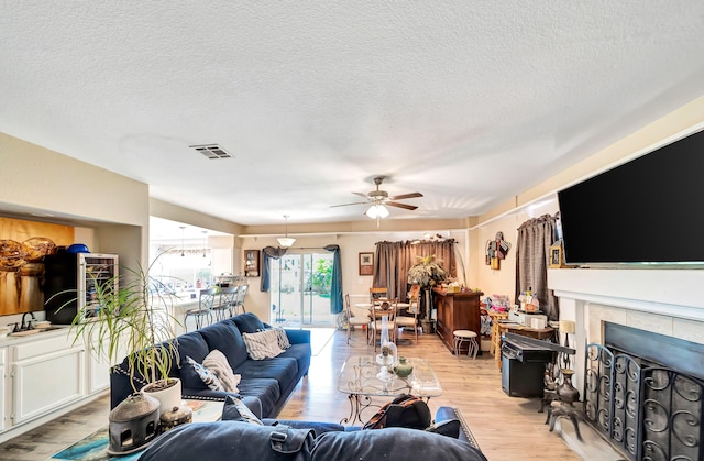 39884 Golfers Dr, Palmdale, CA 93551 - living area featuring ceiling fan, light wood-style floors, a textured ceiling, and a fireplace