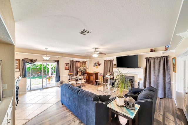 39884 Golfers Dr, Palmdale, CA 93551 - living area featuring ceiling fan, light wood-style flooring, a textured ceiling, and a fireplace