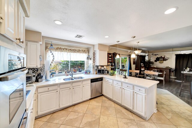 39884 Golfers Dr, Palmdale, CA 93551 - kitchen featuring stainless steel appliances, a sink, a peninsula, light countertops, and white cabinets