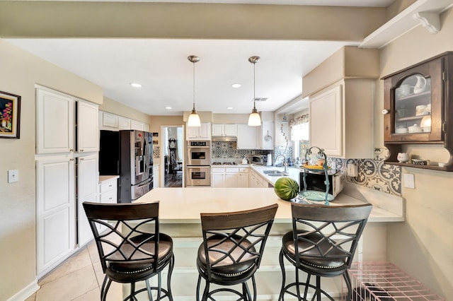 39884 Golfers Dr, Palmdale, CA 93551 - kitchen featuring stainless steel appliances, a peninsula, a breakfast bar, light countertops, and backsplash