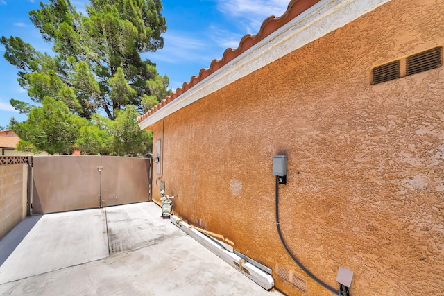 39884 Golfers Dr, Palmdale, CA 93551 - view of home's exterior featuring stucco siding, a patio area, fence, a tiled roof, and a gate