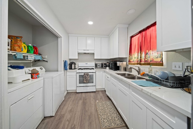 kitchen featuring white gas range oven, washing machine and dryer, and white cabinets