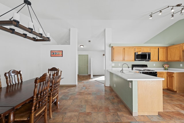 kitchen with stainless steel microwave, gas range, light countertops, vaulted ceiling, and a sink