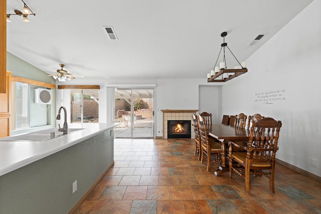 dining area featuring a tiled fireplace, plenty of natural light, baseboards, and visible vents