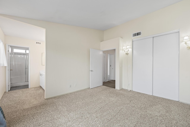 unfurnished bedroom featuring ensuite bath, carpet flooring, and visible vents