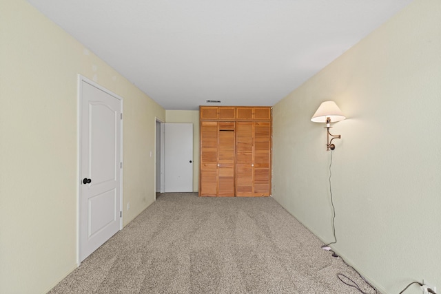 unfurnished bedroom featuring a closet, light carpet, and visible vents