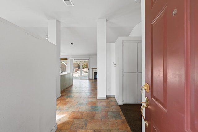 corridor featuring stone finish floor and baseboards