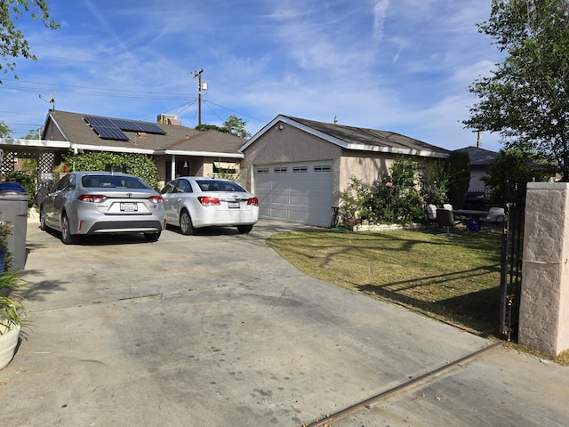 ranch-style home featuring stucco siding, driveway, roof mounted solar panels, and a front lawn
