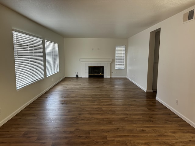 unfurnished living room featuring a tile fireplace and dark wood-type flooring