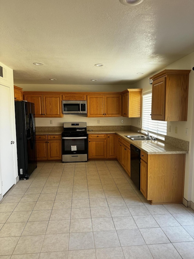 kitchen featuring light tile patterned flooring, sink, light stone countertops, and black appliances