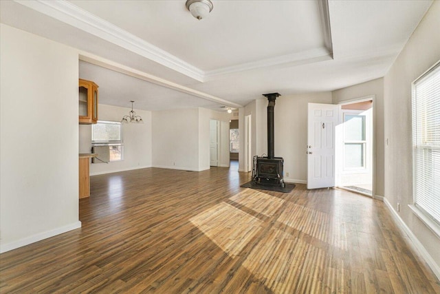 unfurnished living room with dark hardwood / wood-style floors, plenty of natural light, a tray ceiling, and a chandelier