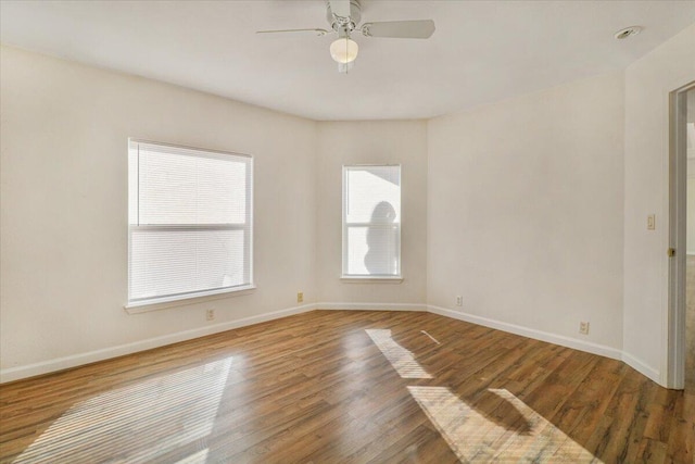 unfurnished room with ceiling fan, dark wood-type flooring, and a wealth of natural light