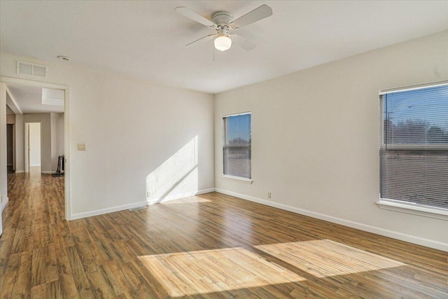 empty room with ceiling fan, plenty of natural light, and dark hardwood / wood-style floors