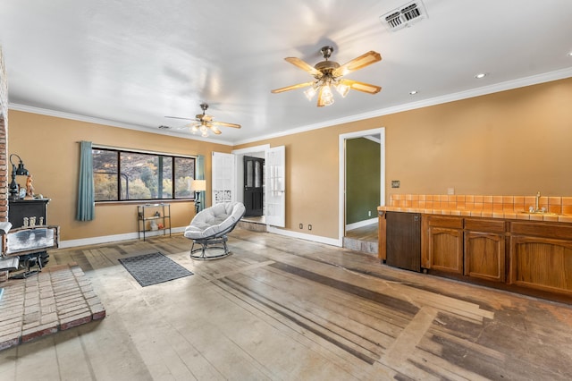 sitting room featuring ceiling fan, crown molding, and sink