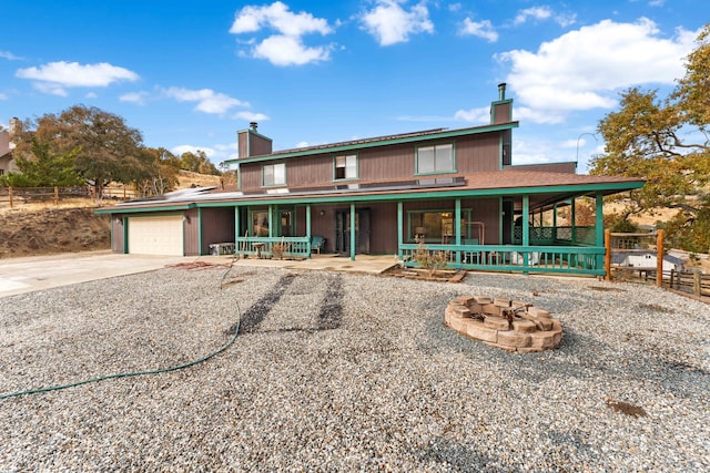 country-style home with covered porch, a garage, and a fire pit