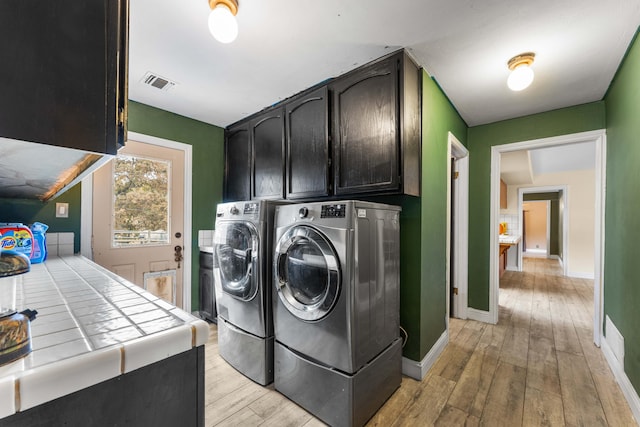 laundry area featuring cabinets, independent washer and dryer, and light wood-type flooring