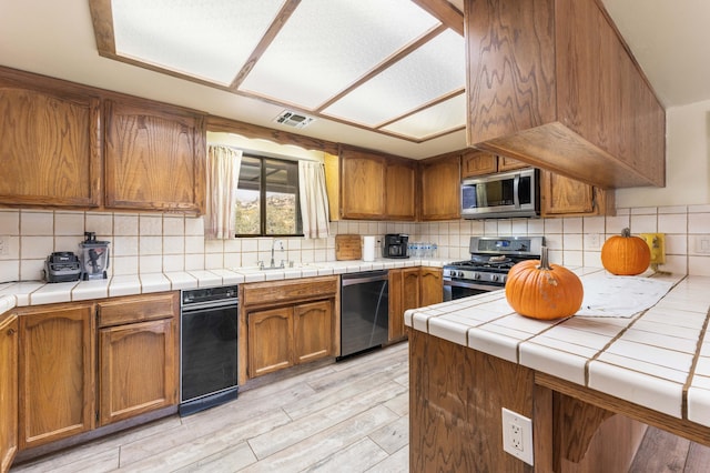 kitchen featuring appliances with stainless steel finishes, backsplash, tile counters, and sink