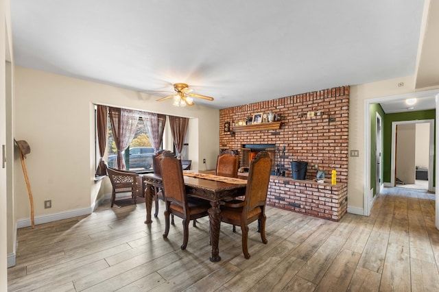 dining space featuring light wood-type flooring, a wood stove, and ceiling fan