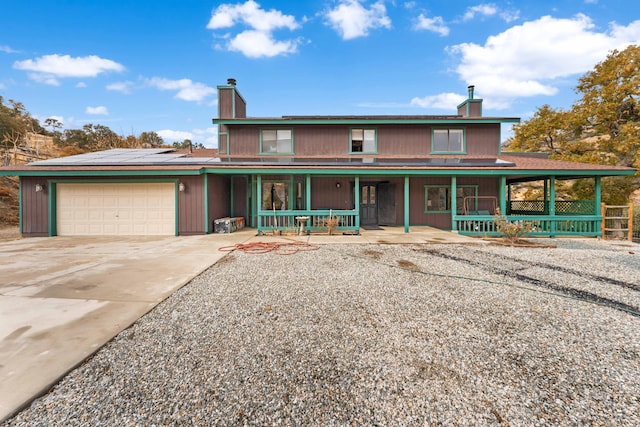 view of front of home with covered porch, solar panels, and a garage