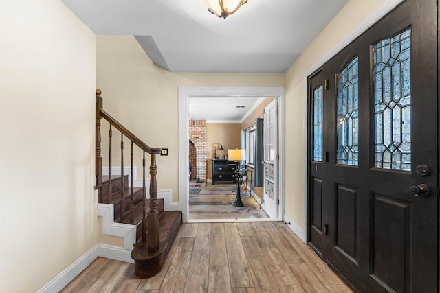 entrance foyer with a healthy amount of sunlight, crown molding, and light hardwood / wood-style flooring