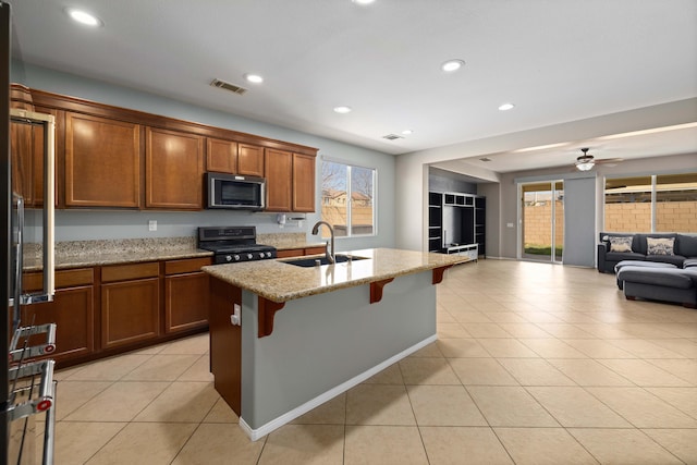kitchen with open floor plan, stainless steel microwave, gas stove, a sink, and visible vents