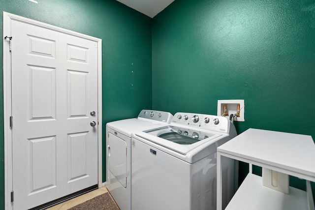 washroom with washing machine and dryer, a textured wall, laundry area, and light tile patterned floors