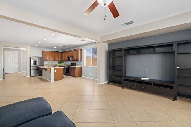 living room with light tile patterned flooring, baseboards, visible vents, and a ceiling fan