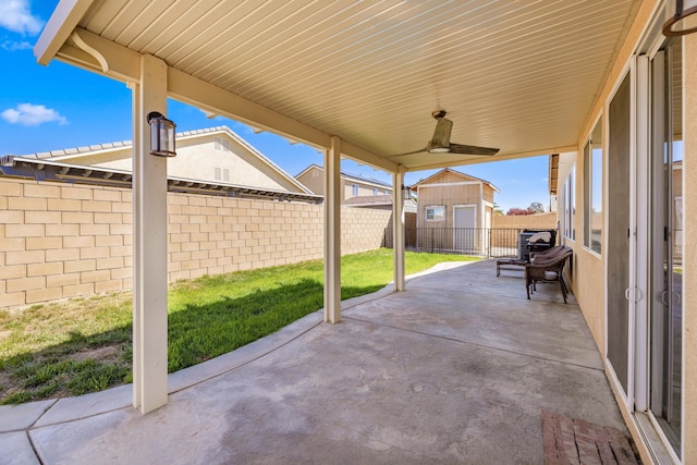 view of patio / terrace with a fenced backyard, an outbuilding, a shed, and ceiling fan