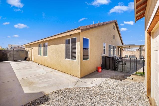 view of side of property featuring fence, stucco siding, and a patio area