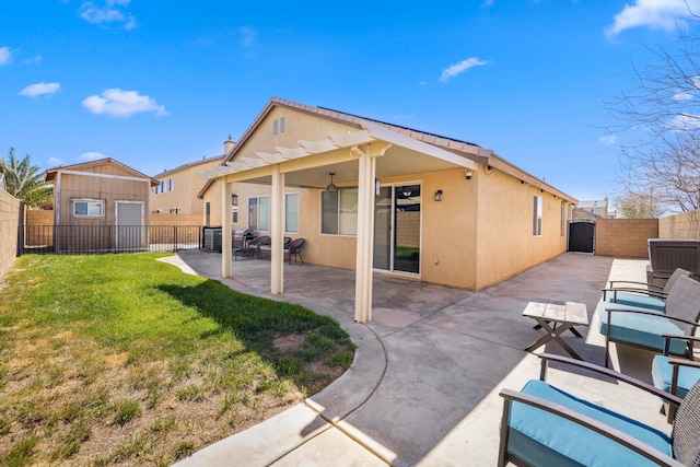 back of house with a fenced backyard, a lawn, stucco siding, and a patio area