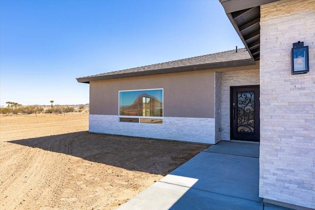 property entrance with stone siding and stucco siding
