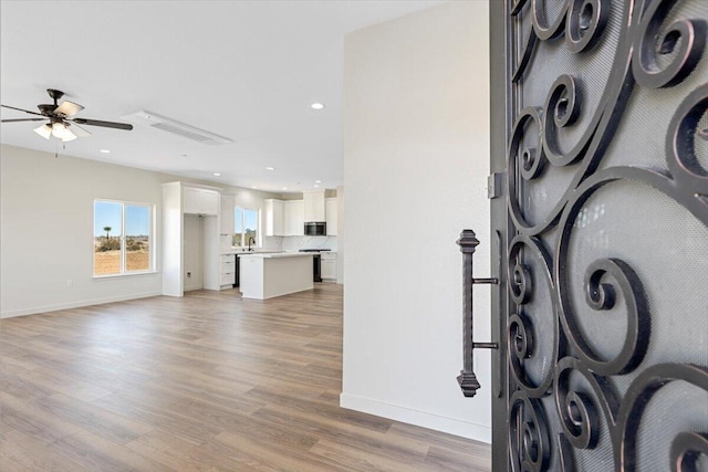 interior space with recessed lighting, light wood-type flooring, a ceiling fan, and baseboards