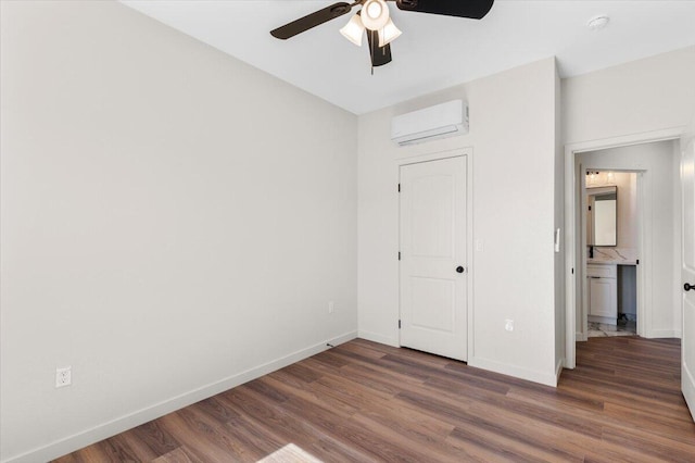unfurnished bedroom with ceiling fan, baseboards, wood finished floors, and a wall mounted air conditioner