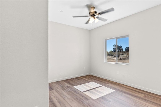 empty room featuring ceiling fan, baseboards, and wood finished floors