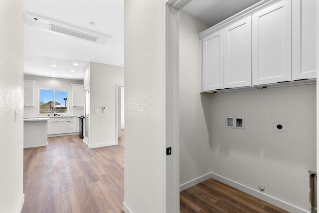 laundry room with gas dryer hookup, wood finished floors, baseboards, cabinet space, and electric dryer hookup