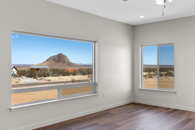 spare room with a mountain view, baseboards, and wood finished floors