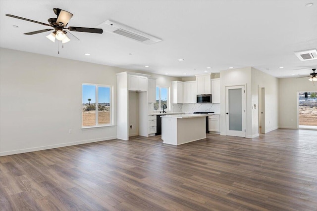 kitchen with a ceiling fan, a wealth of natural light, open floor plan, and stainless steel microwave
