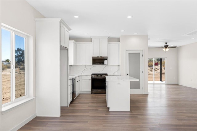 kitchen featuring stainless steel appliances, wood finished floors, light countertops, a center island, and tasteful backsplash
