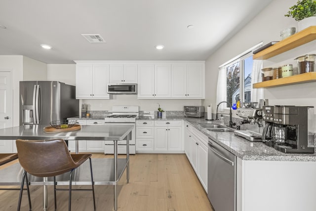 3625 Garnet Ln, Lancaster, CA 93535 - kitchen featuring appliances with stainless steel finishes, a sink, white cabinets, light wood-style floors, and light stone counters