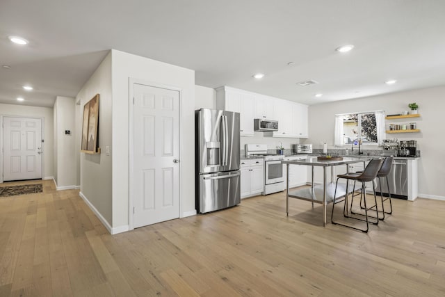 3625 Garnet Ln, Lancaster, CA 93535 - kitchen with appliances with stainless steel finishes, white cabinetry, light wood finished floors, baseboards, and open shelves