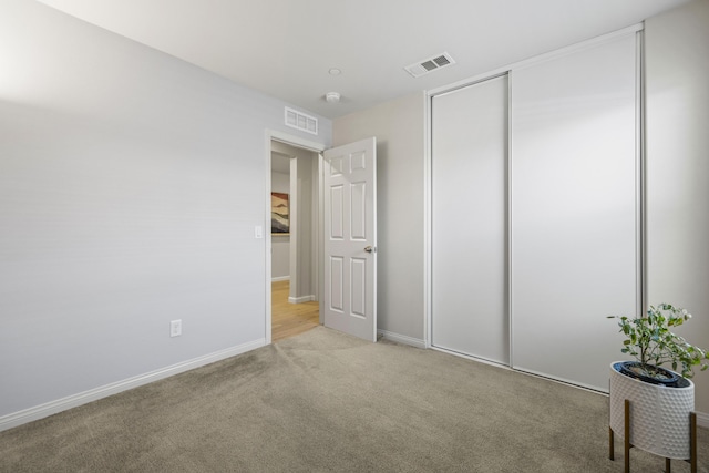 unfurnished bedroom with light carpet and a closet