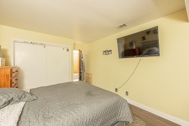 bedroom with baseboards, visible vents, and wood finished floors