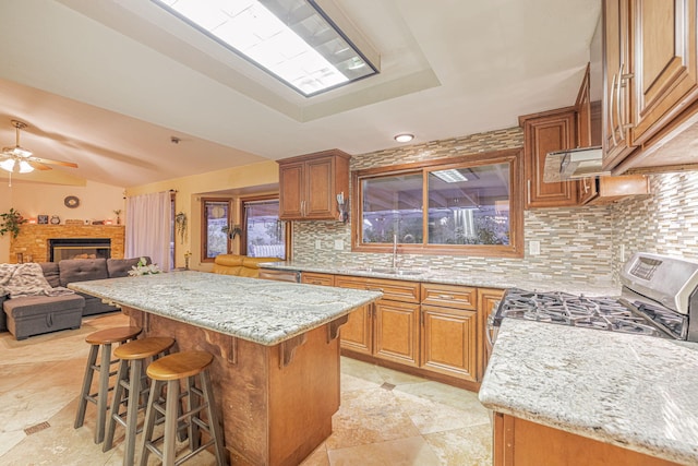 kitchen with a breakfast bar, open floor plan, a center island, a sink, and gas stove