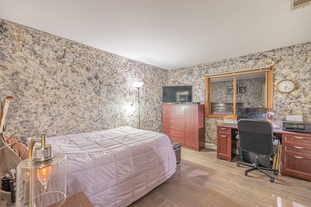 bedroom featuring light wood-style flooring, visible vents, and wallpapered walls