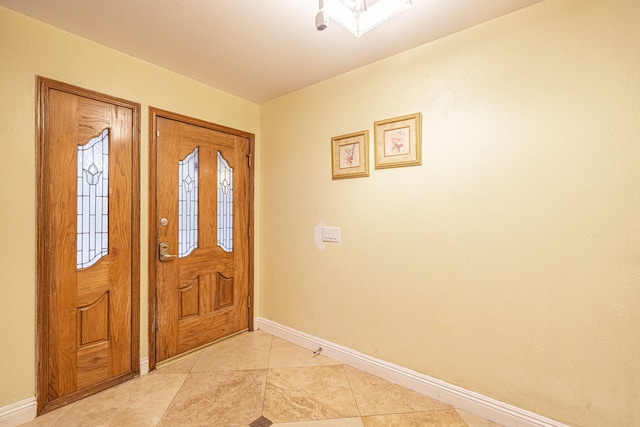 foyer entrance featuring baseboards and light tile patterned floors