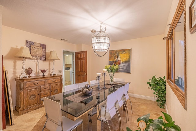 dining area featuring baseboards, washer / dryer, visible vents, and a notable chandelier