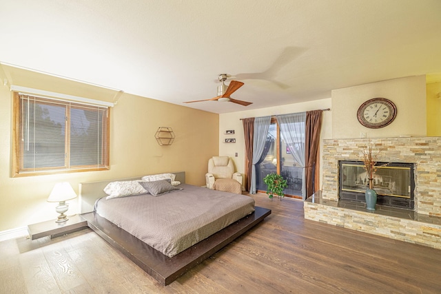 bedroom with baseboards, ceiling fan, wood finished floors, access to exterior, and a fireplace