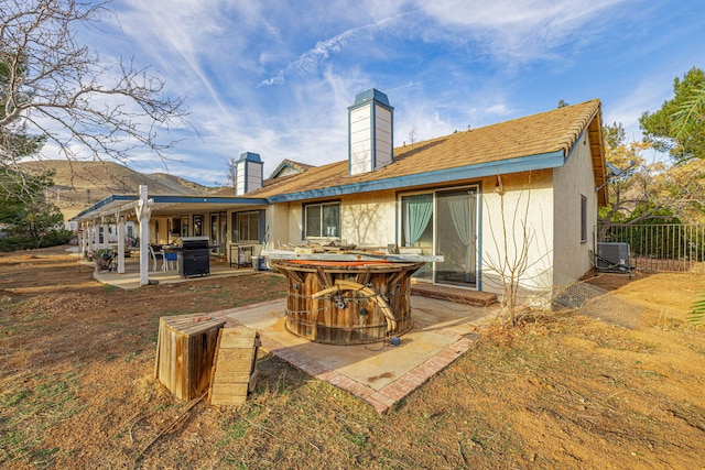 back of house featuring cooling unit, a patio area, a chimney, and stucco siding