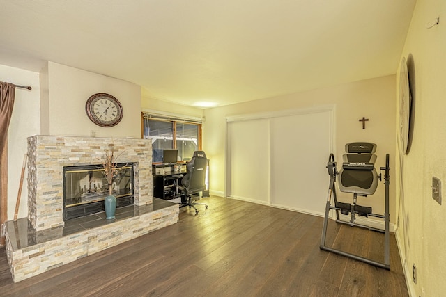 office with dark wood-style floors, a glass covered fireplace, and baseboards