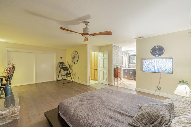 bedroom with wood finished floors, a ceiling fan, visible vents, baseboards, and a closet